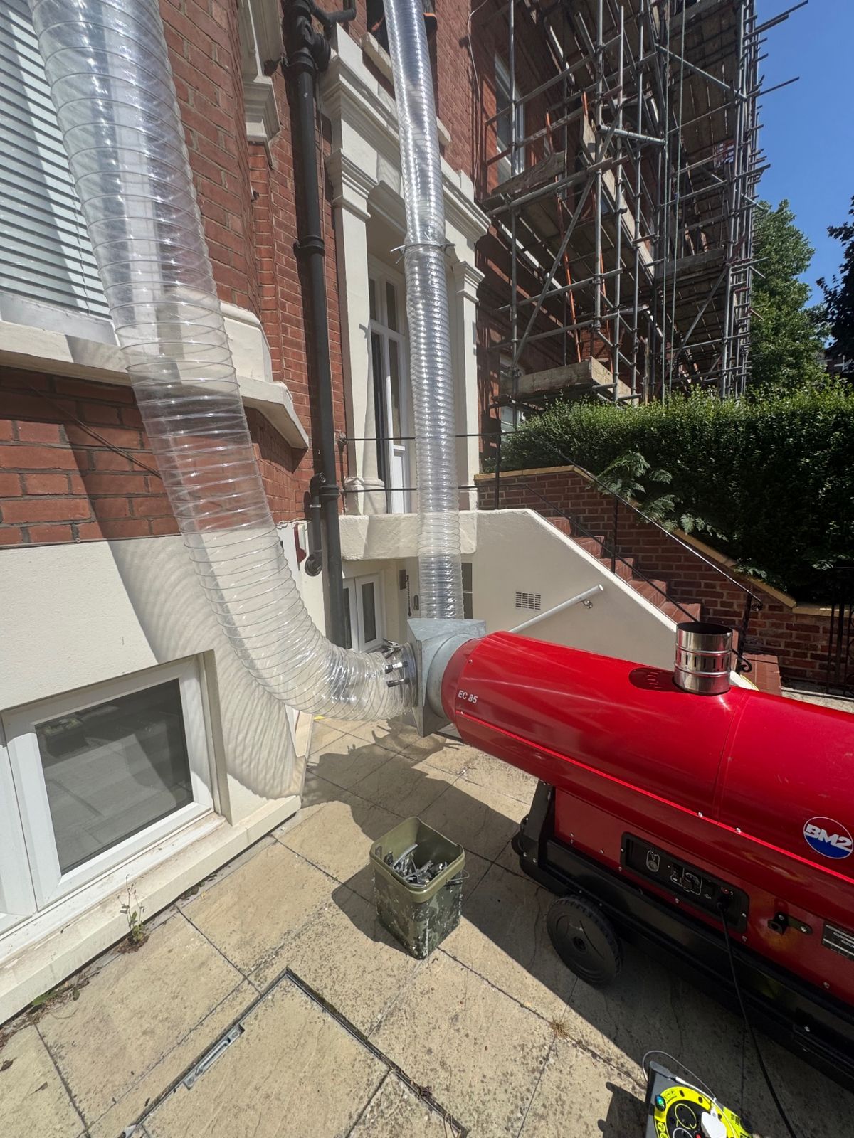 Industrial BM2 Biemmedue EC85 heater with clear ducting feeding heat into a London Victorian property